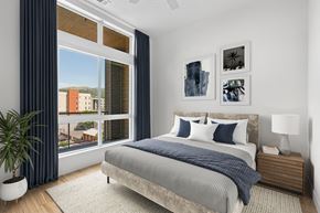 Salt Lake City apartment for rent - A bedroom with a large bed and a view of a cityscape through the window.