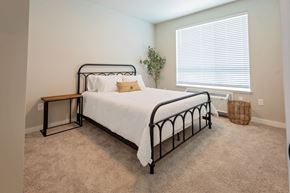 Post Falls apartment for rent - A bedroom with a bed, nightstand, and carpet.