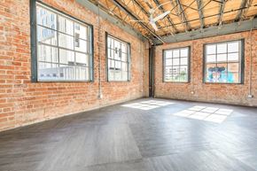 Tucson apartment for rent - A large empty room with wooden floors and brick walls.