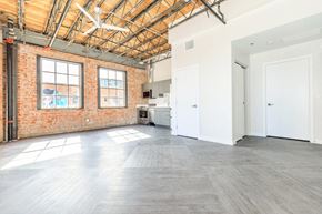 Tucson apartment for rent - A large empty room with a brick wall and wooden ceiling.