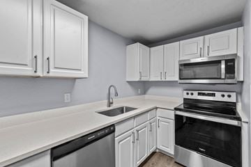 Boise apartment for rent - a kitchen with white cabinets and black and white appliances