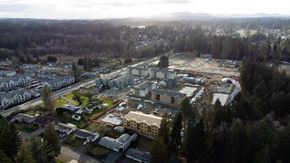 Lacey apartment for rent - Aerial view of The Elowen apartment construction in Lacey WA amid towering evergreen trees on an overcast Pacific Northwest day.