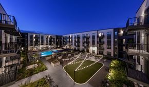 Aurora apartment for rent - A courtyard with a pool surrounded by buildings at night.