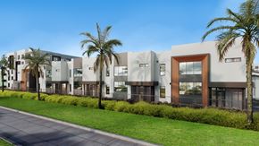 Pompano Beach apartment for rent - A modern building with a row of palm trees in front.