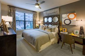 Atlanta apartment for rent - Carpeted bedroom with a bed, nightstand, desk and chair, dresser, and large window facing the pool area.