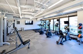Evanston apartment for rent - a gym with cardio equipment and a tv on the wall