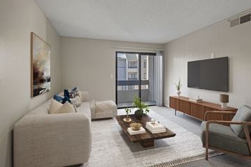 Las Vegas apartment for rent - A living room with a grey couch, a wooden coffee table, a grey armchair, a flat screen TV, and a painting on the wall.