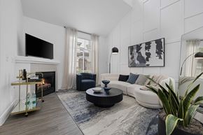 Las Vegas apartment for rent - Modern living room with wood-style vinyl plank flooring, vaulted ceilings, fireplace, television, and window.