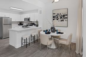 Las Vegas apartment for rent - Dining room and kitchen with breakfast bar, ceiling fan, and wood-style vinyl plank flooring.