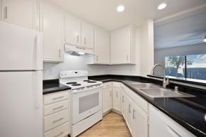 Carlsbad apartment for rent - a kitchen with white appliances, black counter tops and white cabinets.