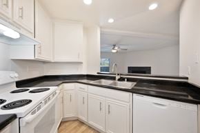 Carlsbad apartment for rent - a kitchen with white appliances, black counter tops, and white cabinets