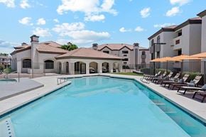 Mesa apartment for rent - A large swimming pool surrounded by lounge chairs and umbrellas.