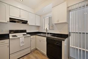 Carlsbad apartment for rent - a kitchen with white cabinets and black counter tops and white appliances