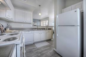 Reno apartment for rent - A white refrigerator stands in a kitchen with white cabinets and a white stove.