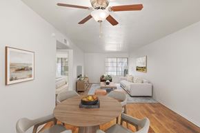 Kingman apartment for rent - Dining room with wood-style vinyl plank flooring and ceiling fan with view to living room with large window.