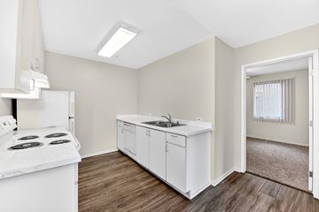San Diego apartment for rent - A kitchen with white appliances and cabinets with a window in the background.