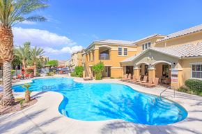 Las Vegas apartment for rent - Wide view of gorgeous pool and community exterior with palm trees and blue sky.