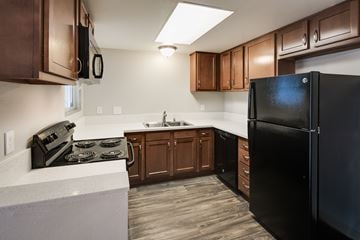 El Cajon apartment for rent - A black refrigerator is in a kitchen with brown cabinets.