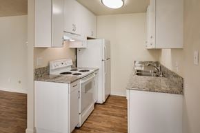 La Mesa apartment for rent - Apartment kitchen with white appliances, white cabinets, and wood-style plank flooring.