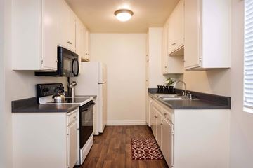 La Mesa apartment for rent - A kitchen with white cabinets and black countertops.