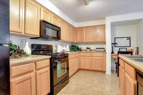 Las Vegas apartment for rent - Kitchen with light wood cabinets and black microwave and gas stove/range.