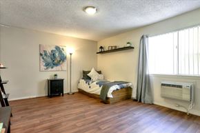 Las Vegas apartment for rent - Private bedroom with wood-style vinyl plank flooring, window, and wall unit air conditioning.