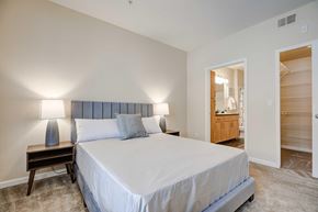Denver apartment for rent - A bedroom with a large bed and a wooden nightstand.