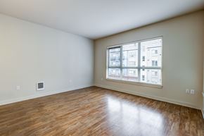 Seattle apartment for rent - A room with wooden flooring and a window showing a building outside.