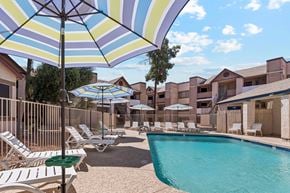 Glendale apartment for rent - Exterior view of apartment pool area with seating under umbrellas.