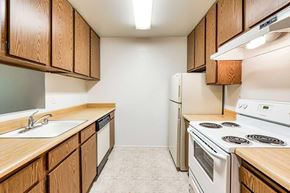 Coalinga apartment for rent - A kitchen with wooden cabinets and white appliances.