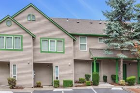 Des Moines apartment for rent - Community exterior with tan siding and green and white accents with shrubs and pine trees.