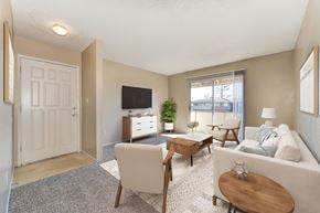 Modesto apartment for rent - A living room with carpet, a couch, 2 chairs, a rug, and a coffee table. In the background you can see a sliding glass door that leads to a balcony.