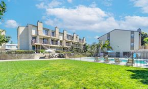 Carlsbad apartment for rent - an apartment building with a lawn and a pool in front of it