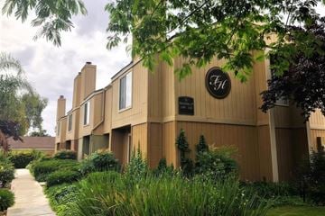 Porterville apartment for rent - A building with a logo on the front and a walkway leading to it.
