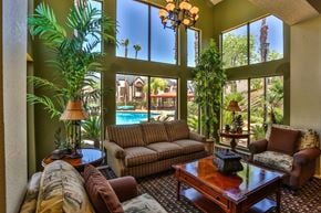Henderson apartment for rent - Community clubhouse with couches, armchairs, and plants, with a view of community pool in the background.