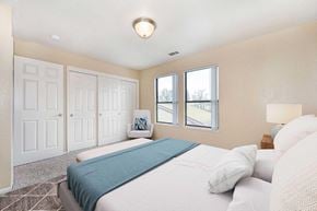 Modesto apartment for rent - A bedroom carpet, off-white walls, and 2 windows. The room is staged with a bed, chair, a rug, and nightstand.