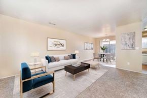 Modesto apartment for rent - A living room with carpet and 2 windows. The room is staged with a couch, chairs, and a coffee table.