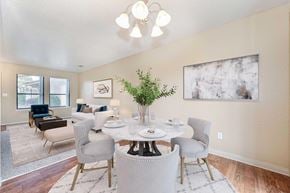 Modesto apartment for rent - A dining room with wood style vinyl flooring, off-white walls, and 2 windows. The room is staged with a dining room table and chairs.