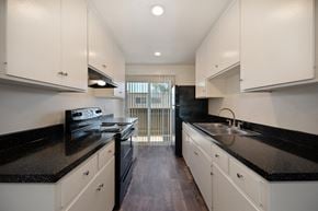 Carlsbad apartment for rent - a kitchen with white cabinets and black counter tops and a stove and sink