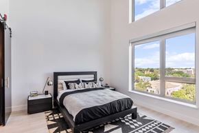 Sacramento apartment for rent - A bedroom with white walls, light colored hardwood floors and big walls bringing in great natural lighting. The room is staged with a bed and a rug.