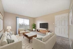 Ceres apartment for rent - A living room with beige walls, a sliding glass door to a balcony, and carpet the room is staged with a couch, a wooden coffee table, and a flat-screen TV mounted on the wall.