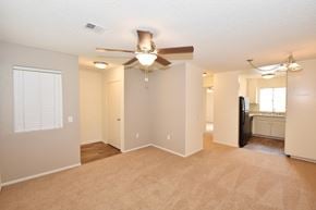 Oceanside apartment for rent - an open living room with a ceiling fan and a kitchen in the background