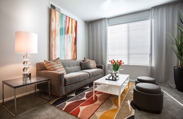 Phoenix apartment for rent - A modern living room with a grey couch, a white coffee table, and a large abstract painting on the wall.