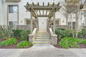 San Diego apartment for rent - A white building with a wooden pergola and a stone wall with steps leading up to the entrance.