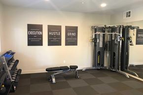 San Diego apartment for rent - A gym with a wall of three signs that read Execution, Hustle, and Grind.