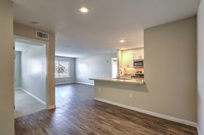 San Diego apartment for rent - A spacious room with wood flooring and a kitchen area in the background.