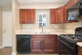 San Diego apartment for rent - A kitchen with dark wood cabinets and black appliances.