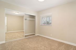 San Diego apartment for rent - A bedroom with a carpeted floor and a closet with a mirror.