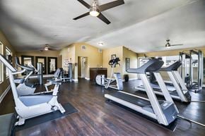 Redlands apartment for rent - A spacious gym with treadmills, elliptical machines, and a fan.