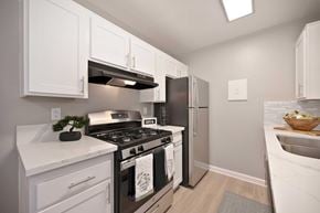 Redlands apartment for rent - A modern kitchen with white cabinets, quartz countertops, and stainless front appliances.